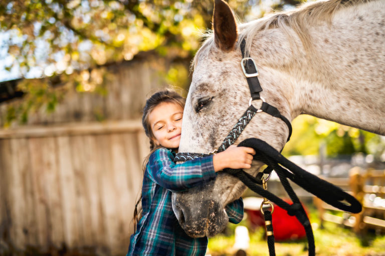 girl child hugging horse face