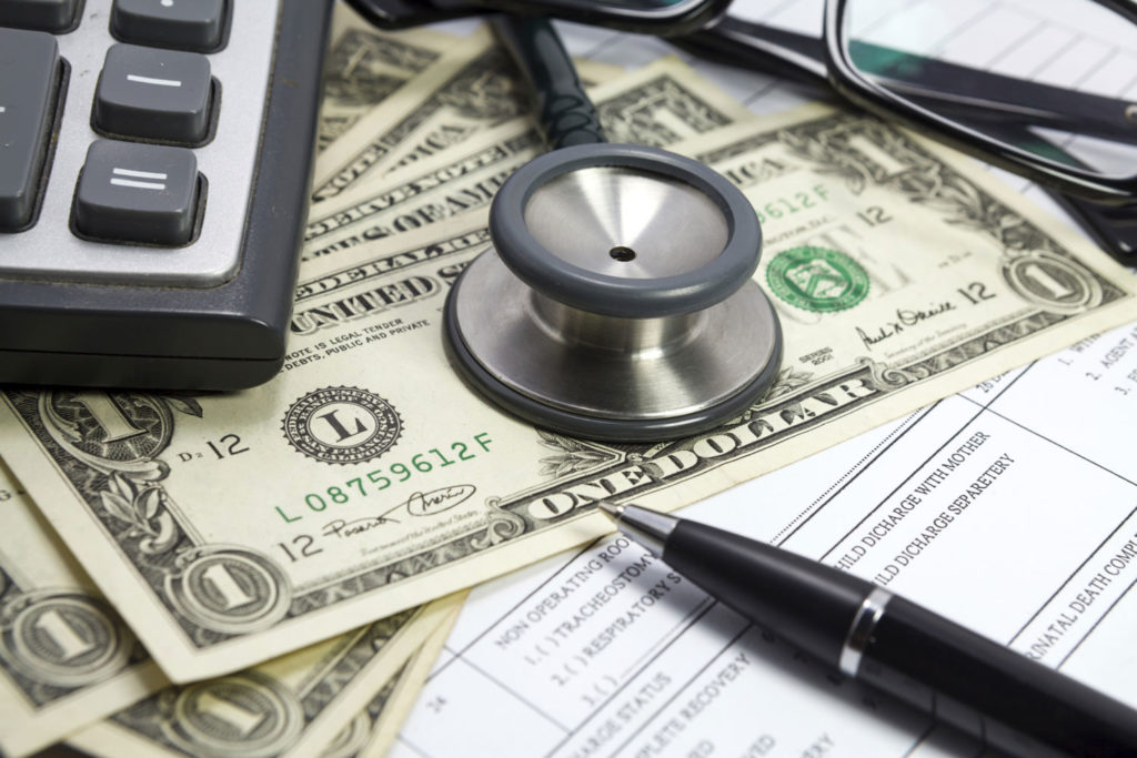 A stethoscope sitting on dollar bills, representing veterinary revenue.