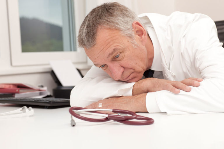 vet male older head on desk tired