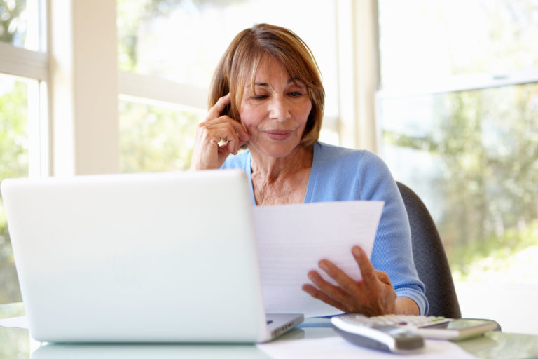 woman older computer paperwork home