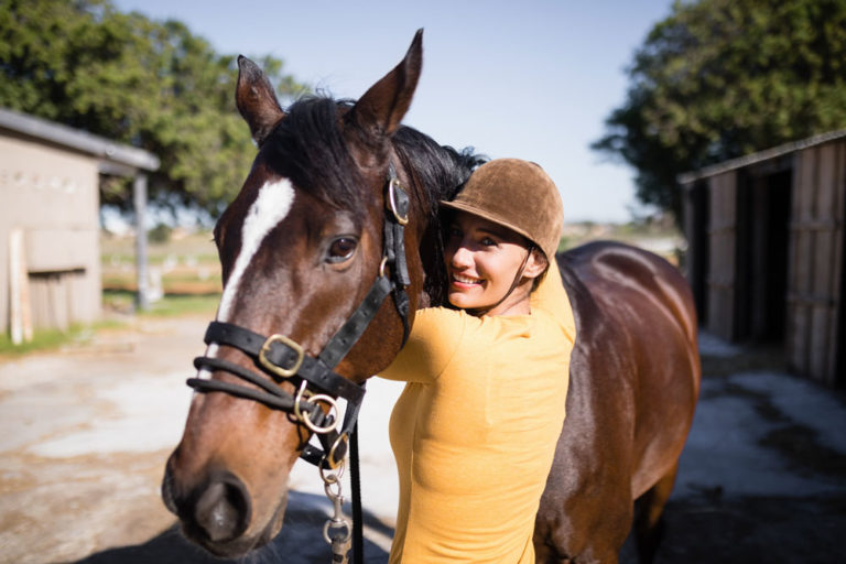 young woman hugging horse outside