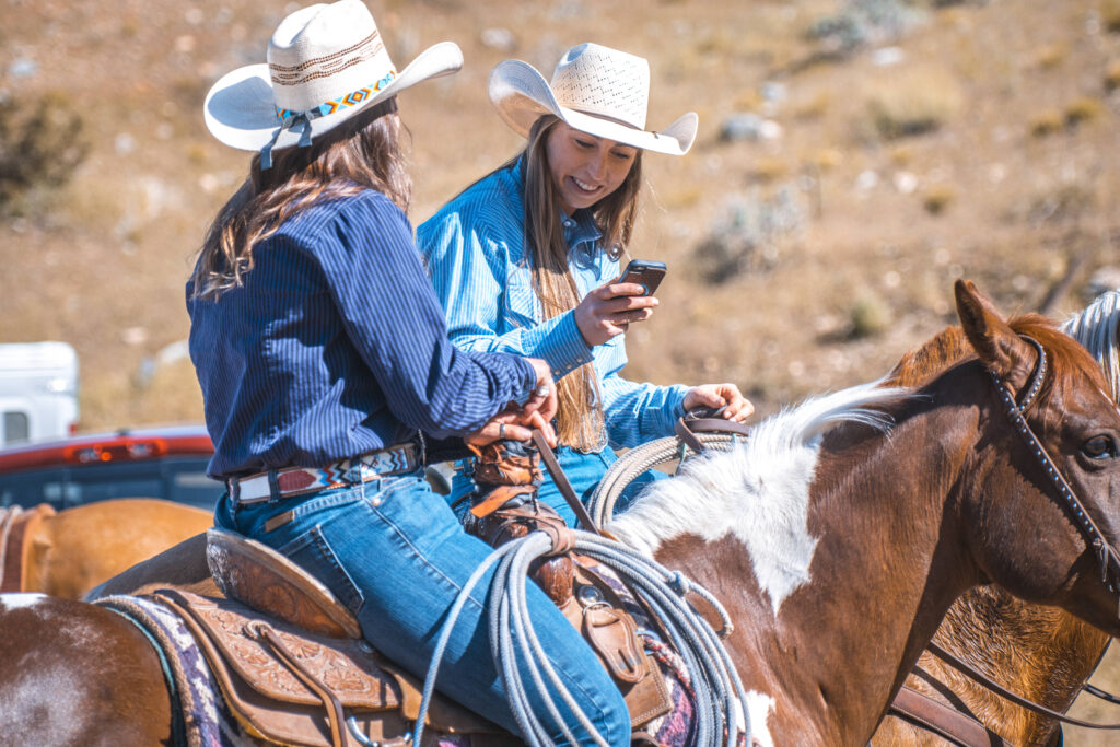 Two Western horsewoman pause to talk and share phone pics. These social media tips for veterinarians will help your practice better connect with these people.