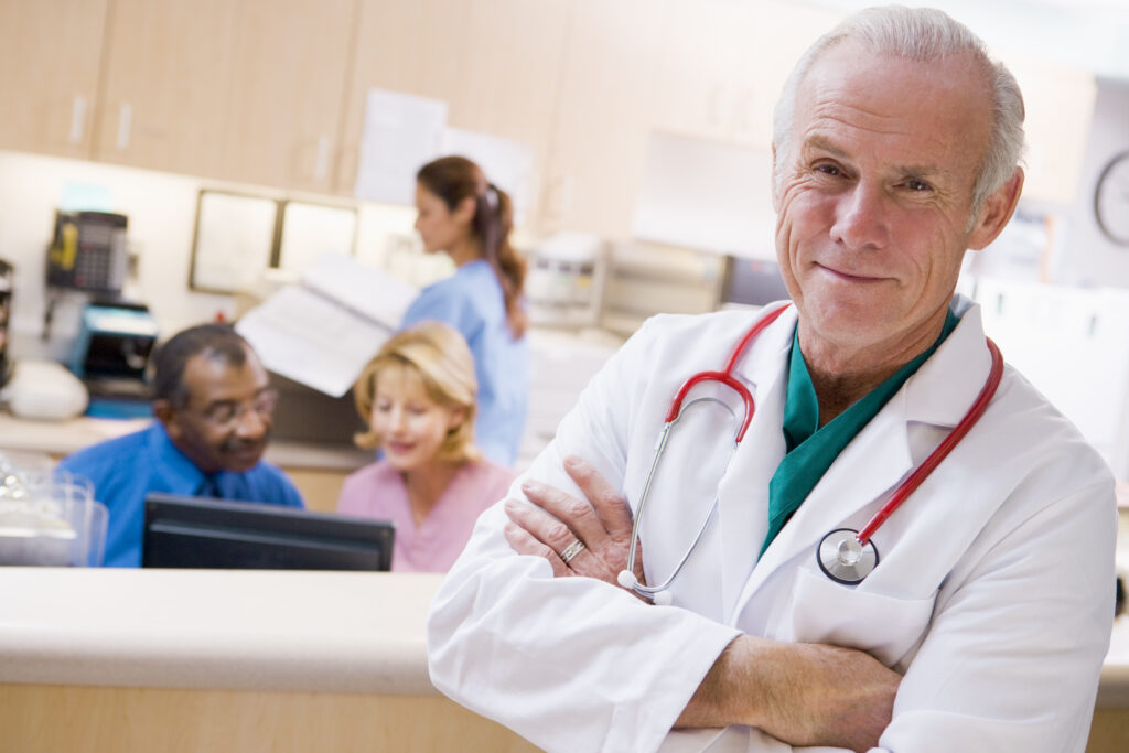 A veterinarian stands in front of his office staff. Having the right staff will help attract clients to your veterinary practice. 