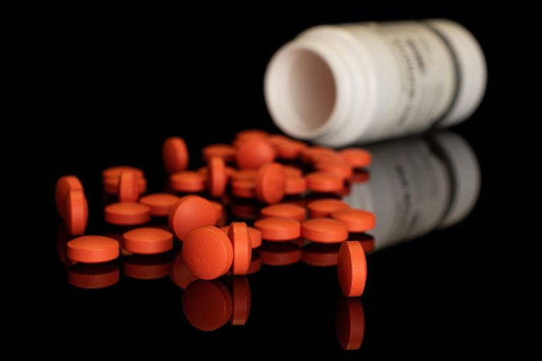 Orange pharmacy tablet isolated on black glass
