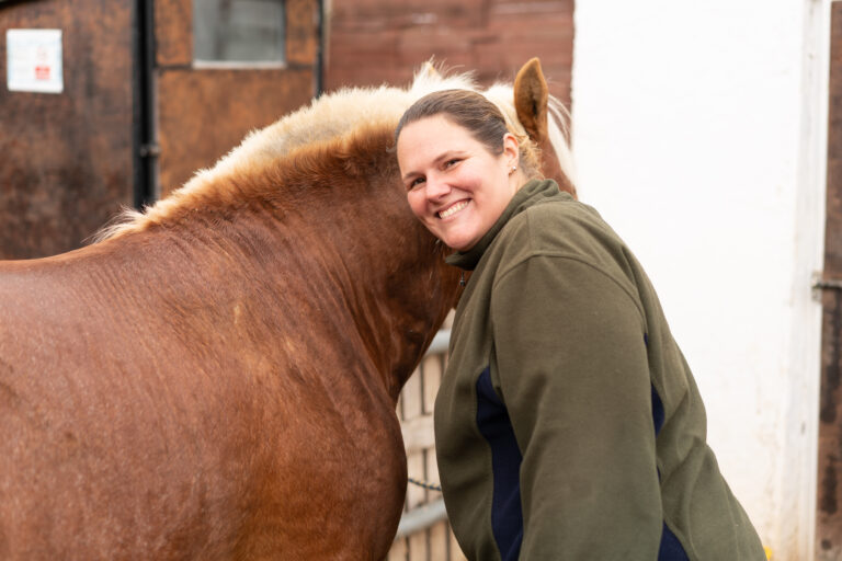 Woman hugging horse looking at camera