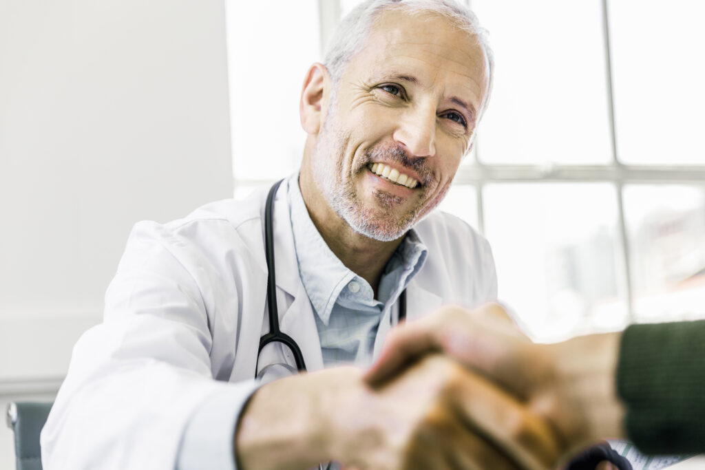 A veterinarian smiling and shaking someone's hand.