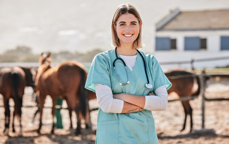 Happy young female veterinarian with horses