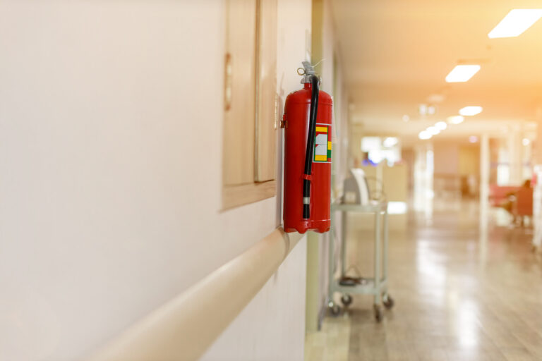 Fire extinguisher in the operating department . Install a fire extinguisher on the wall in building. Dry chemical powder fire extinguisher in corridor .a red fire-extinguisher hangs on wall 