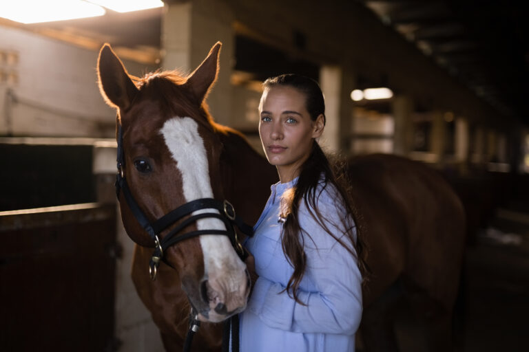 Confident female vet standing by horse in stable