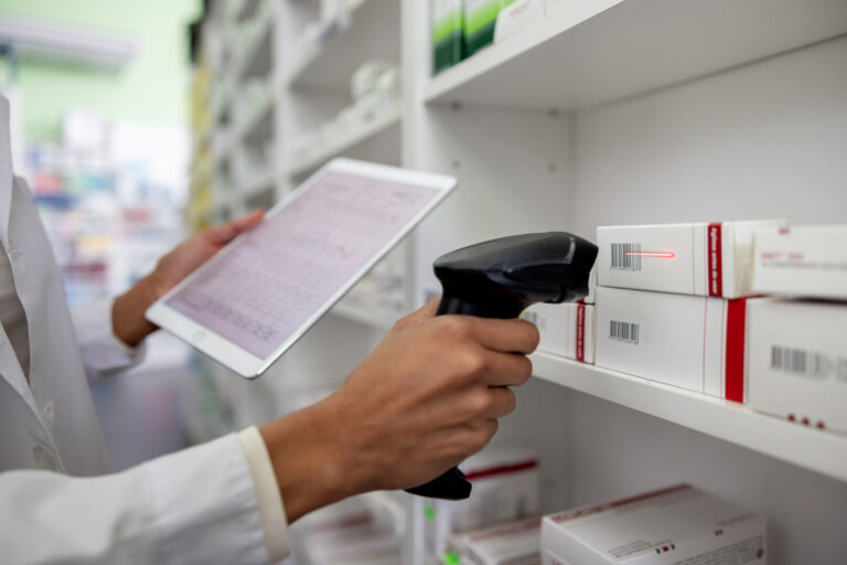 Pharmacist taking inventory at the drugstore using a bar code reader