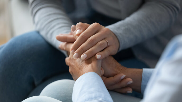 Adult daughter comforting old mother strokes her hand closeup view