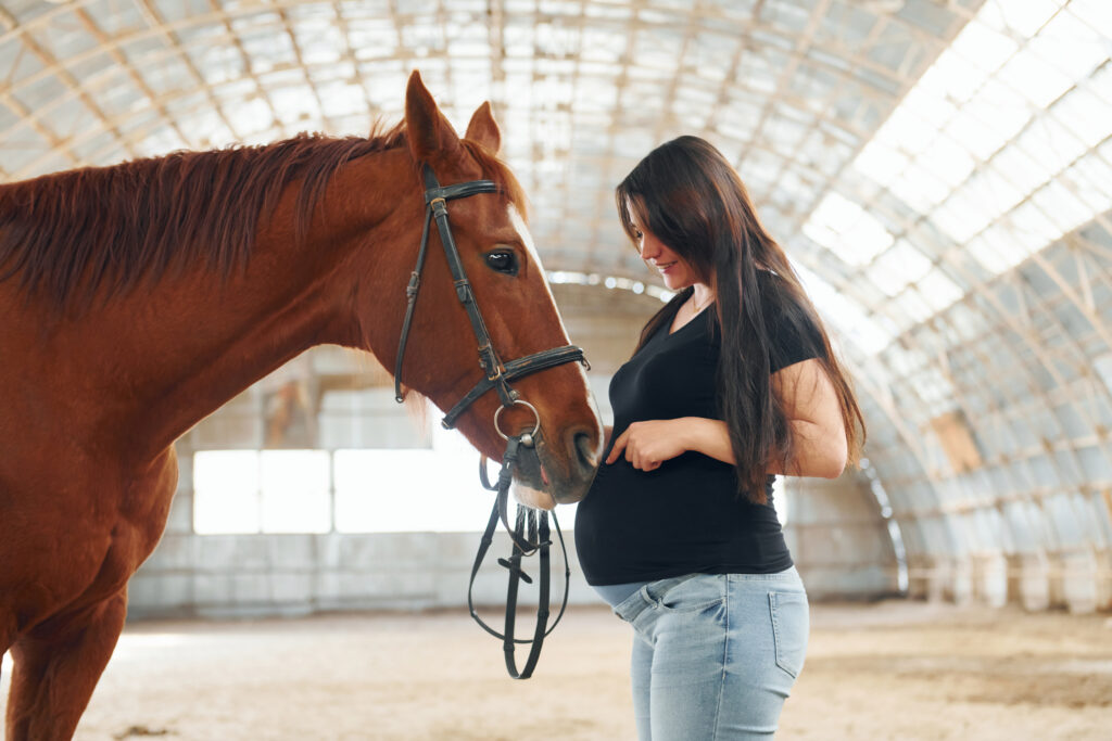 Pregnant woman with horse, pregnant equine veterinarian with horse