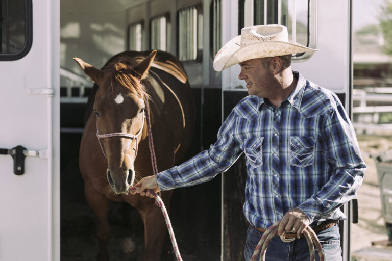 A man taking his horse out of a horse trailer