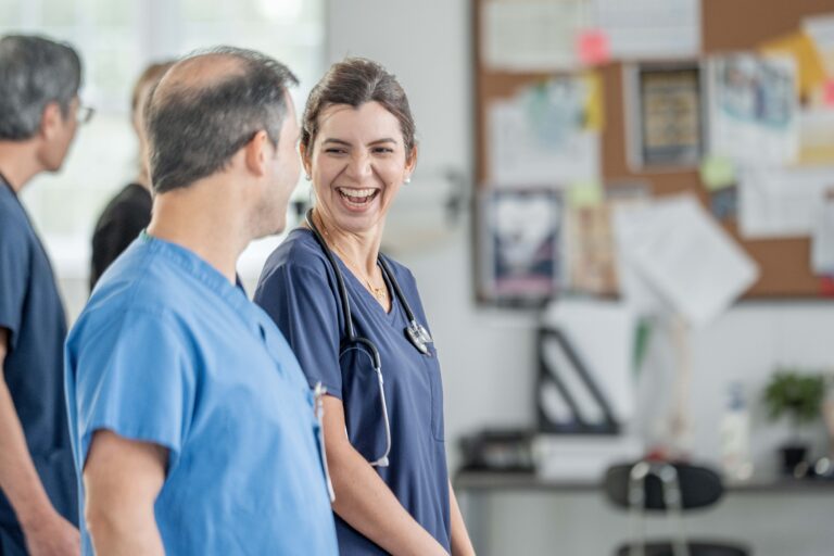 Smiling Nurse Interacts With Colleague In Modern Clinic Office Setting During Break