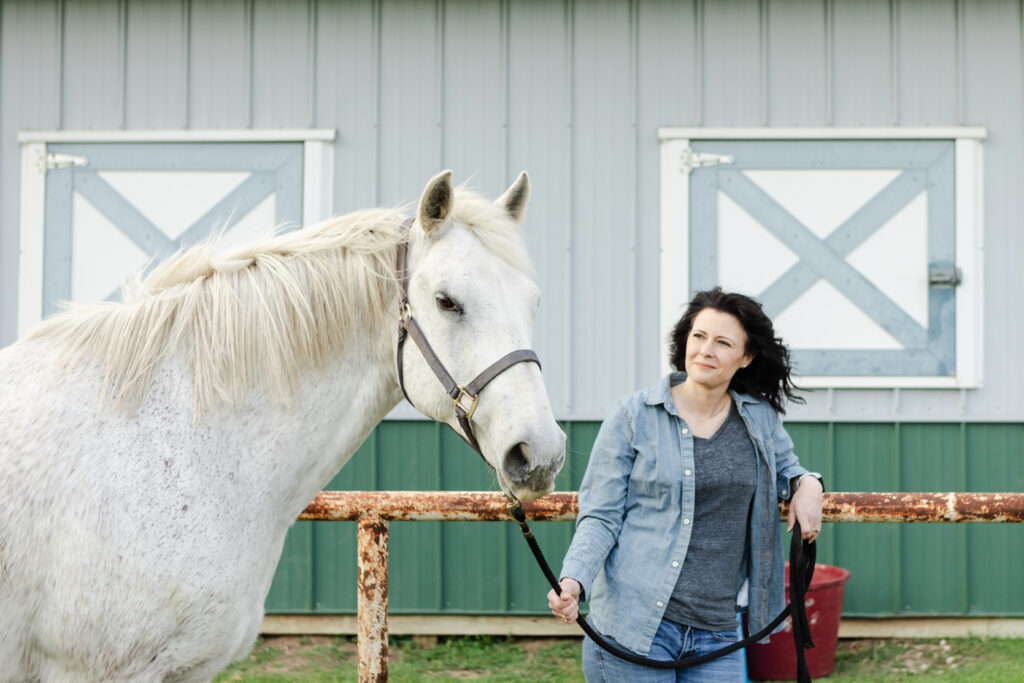 Equine veterinarian standing next to a grey horse.