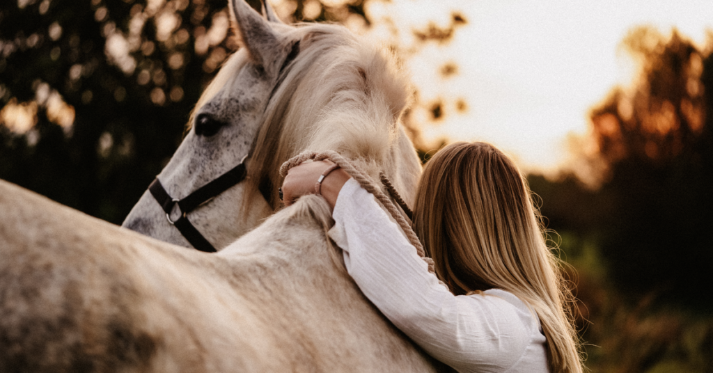 Girl embracing her horse, practicing self-compassion. 
